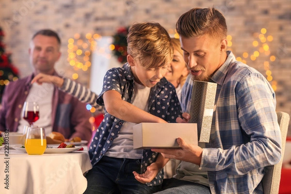 Fototapeta Father and son opening Christmas gift at home