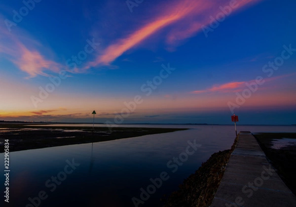 Fototapeta sunset with calm water and high clouds