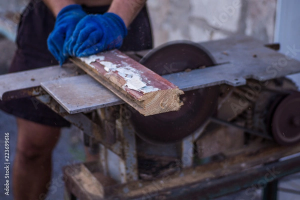 Fototapeta A man is sawing wood on a sawmill, prepared for the winter, makes logs