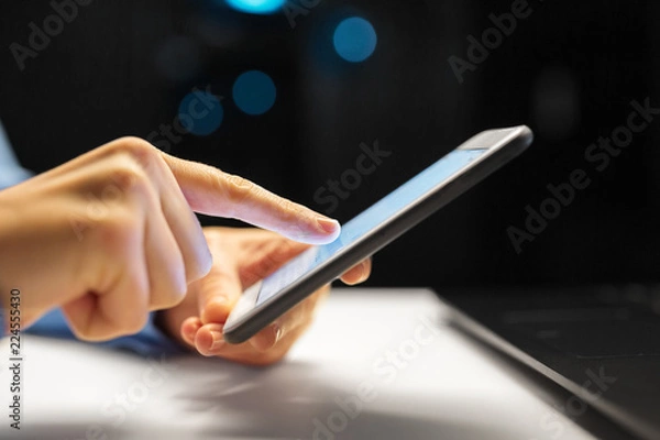 Obraz business, deadline and technology concept - close up of businesswoman hands with smartphone at night office