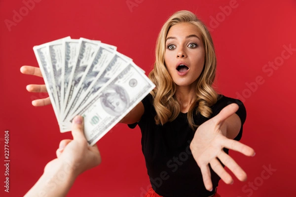 Fototapeta Woman looking at money which someone gives to her isolated over red background.