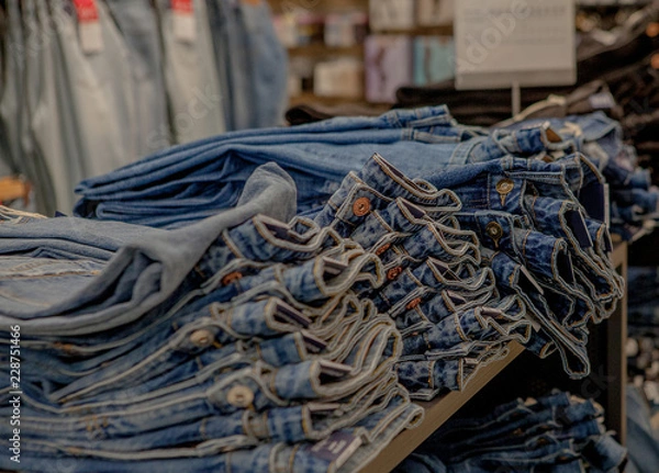 Fototapeta Piles of jeans on a counter in shop. Fashion and shopping concept