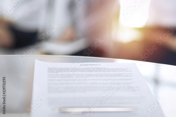 Fototapeta Contract with a pen and blurred business people on the background, close-up. Female candidates waiting for interview at queue