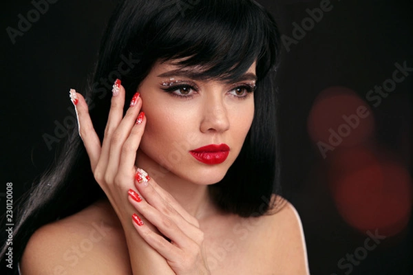 Fototapeta Christmas red lips makeup and Manicured nails. Beautiful brunette girl closeup portrait. Sensual young woman with xmas eye shadow and long eyelashes. Vogue style visage. Studio photo.