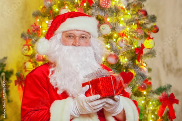 Fototapeta Santa Claus with giftbox on background of sparkling firtree