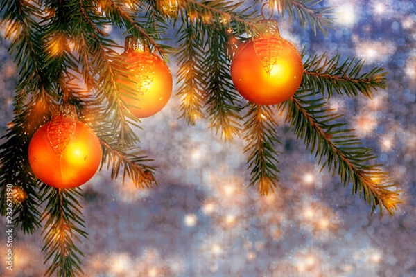 Fototapeta Orange Christmas ornaments on spruce branches on a shiny blue-silver background. New Year's or Christmas background