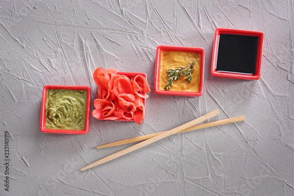 Fototapeta Different tasty sauces with marinated ginger in bowls on grey background