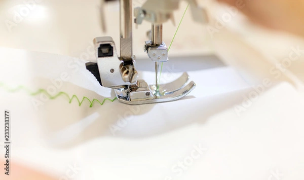 Fototapeta Close up - Female tailor working with sewing machine. professional woman hands during sewing work with yarn on sewing machine. Zigzag. Selective focus.