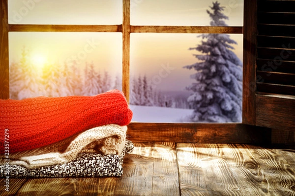 Fototapeta Winter window and start wooden table with warm cloths   