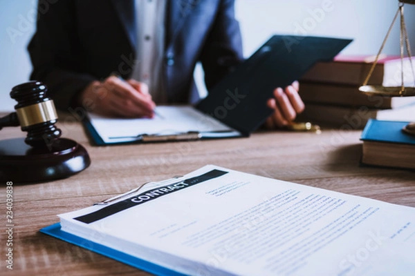 Fototapeta Close up of hand lawyer working signing contract paper with wooden gavel judge in the office. lawyer and law ,judiciary and legislature courtroom legal concept.