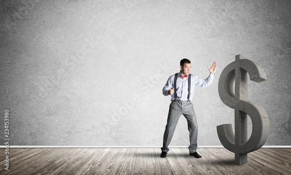 Fototapeta Determined banker man in empty concrete room breaking dollar figure