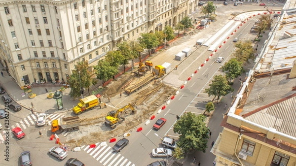 Fototapeta Orange construction telescopic mobile crane loading old tram rails into truck timelapse.