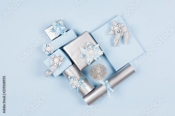 Fototapeta Modern soft minimalist heart shape - various blue and silver metallic gift boxes with shiny ribbons and bows on blue color backdrop, top view. Valentines day background.