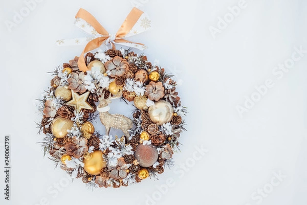 Fototapeta Top view Beautiful hand made golden Christmas wreath decorated with pine cones, ornamentals, spruce branches, balls, stars and decorative deer on white background isolated, flat lay. Copy space.