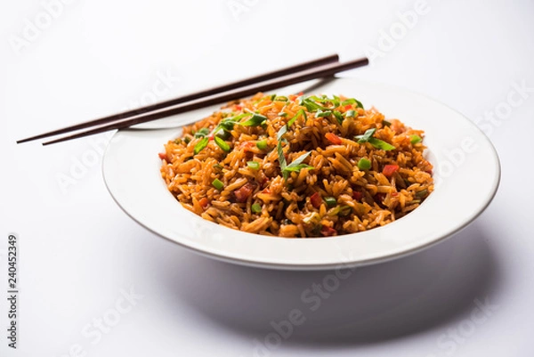 Fototapeta Schezwan Fried Rice Masala is a popular indo-chinese food served in a plate or bowl with chopsticks. selective focus