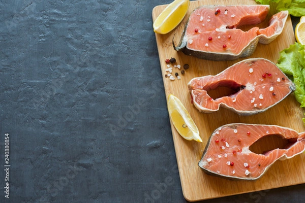 Fototapeta Steak raw red fish with lemon and spices dark background with copy space.