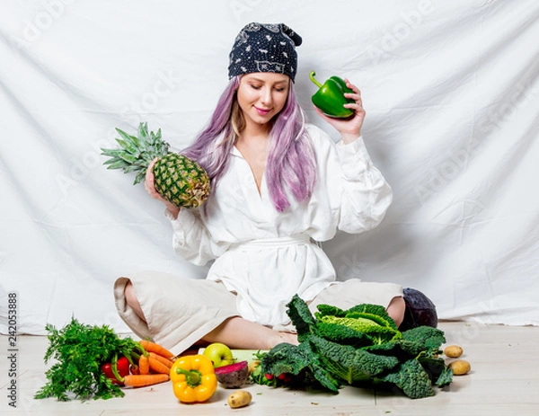 Fototapeta Beautiful caucasian vegan woman with vegetables sitting on a flooor. Spring time concept and healthy meal