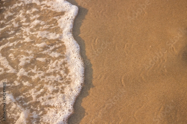 Fototapeta The wave rolls on the sand