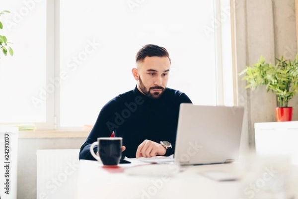 Fototapeta Caucasian young man working on laptop