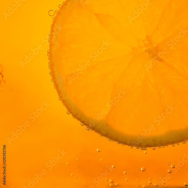 Fototapeta orange slice with bubbles on orange background.