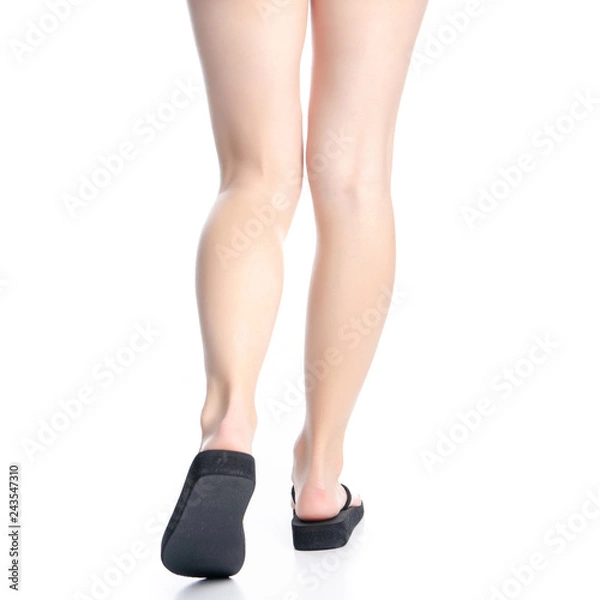 Fototapeta Woman legs in black flip flops on white background isolation, back view