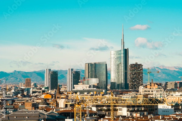 Fototapeta Milan skyline with modern skyscrapers in Porta Nuova business district in Italy. Panoramic view of Milano city. The mountain range of the Lombardy Alps in the background.