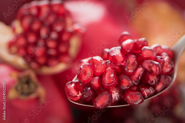 Fototapeta Spoon with pomegranate seeds on fresh ripe pomegranates background 3