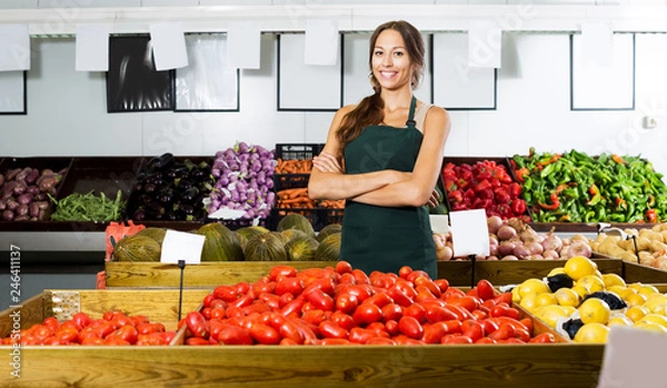 Fototapeta Woman in apron selling organic tomatoes in shop