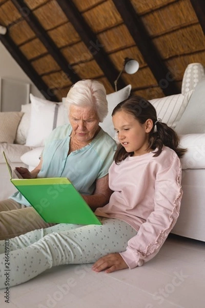 Fototapeta Grandmother and granddaughter reading story book 