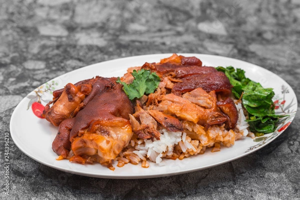 Obraz German pork knuckle with rice, vegetable and fruit served with sauce on wooden table.