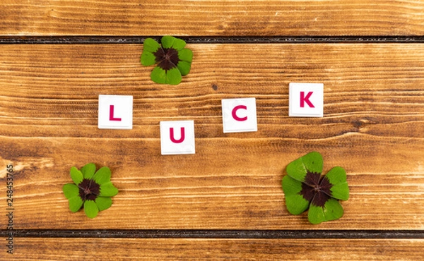 Fototapeta text luck on a wooden background with ucky clover