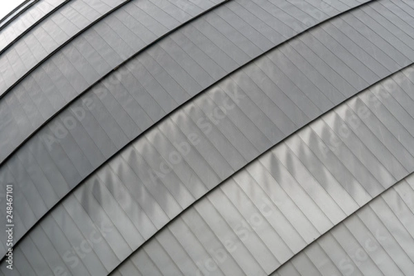 Fototapeta Metallic roof top with rounded lines in urban environment, dark grey, suitable as background