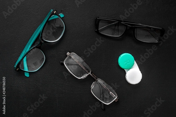 Obraz Eye problems. Glasses with transparent lenses and contact lenses on black background top view