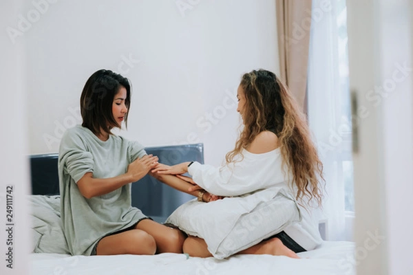 Fototapeta Happy Family teenage daughter is applying lotion to the mother in the bedroom in the morning.