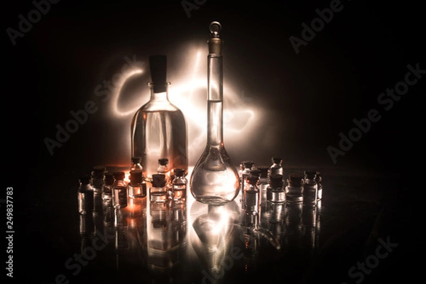 Fototapeta Pharmacy and chemistry theme. Test glass flask with solution in research laboratory. Science and medical background. Laboratory test tubes on dark toned background