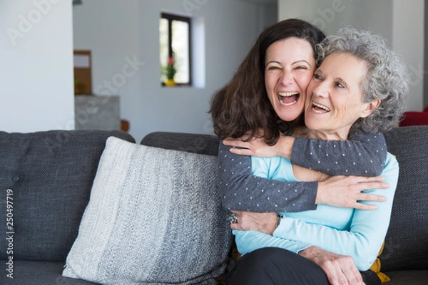 Fototapeta Portrait of happy mid adult woman embracing her senior mother