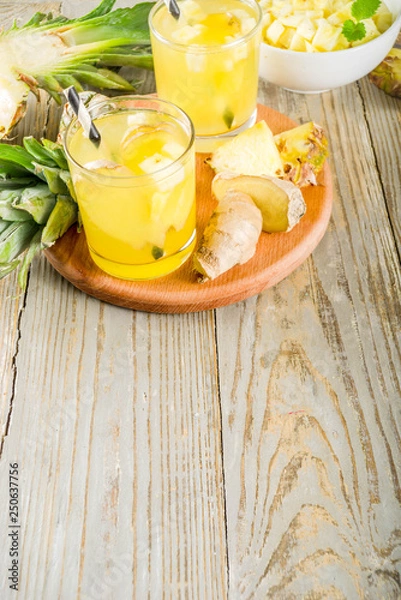 Fototapeta Healthy and immunity diet drink. Ginger and pineapple cold tea, infused water, Wooden background copy space