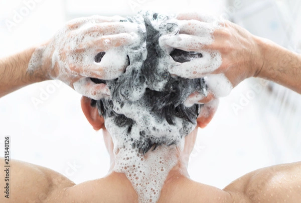 Fototapeta Closeup young man washing hair with with shampoo in the bathroom, health care concept, selective focus