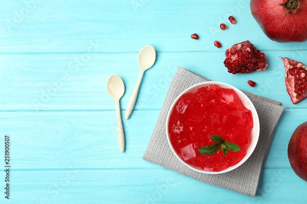 Fototapeta Flat lay composition with red jelly in bowl and pomegranate on wooden background. Space for text