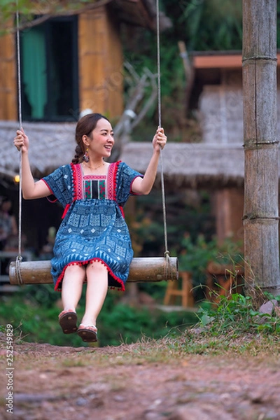 Fototapeta asian girl on bamboo swing in holiday by posing smile relaxation in nature mountain and countryside village by wearing lanna dress north thailand