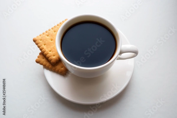 Fototapeta Cup of black coffee with crackers on saucer on white background