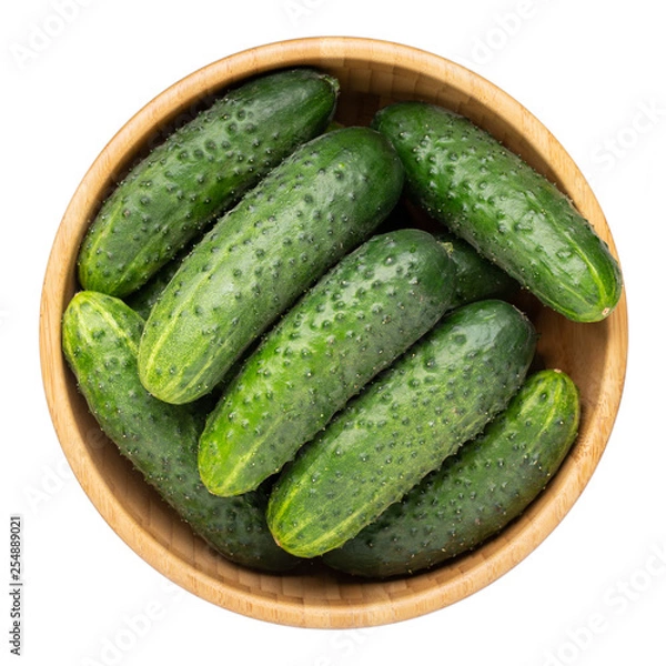 Fototapeta Whole cucumbers in wooden bowl isolated on white. Top view.