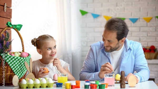 Fototapeta Cute father and daughter painting eggs, preparation for Easter celebration