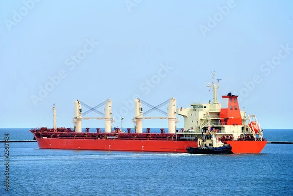 Fototapeta Tug boat helps to maneuver the ship