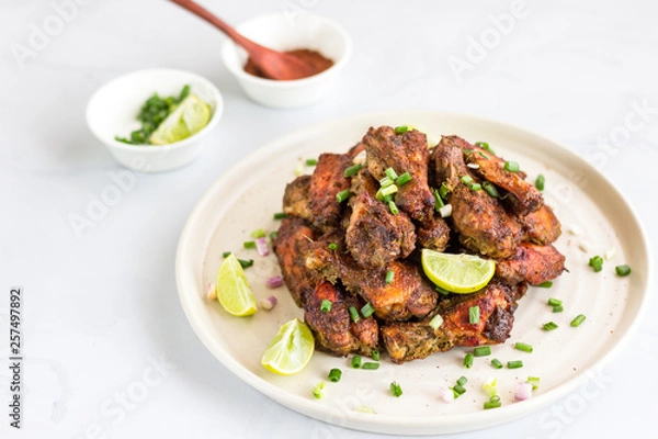 Fototapeta Jamaican Jerk Chicken Wings ona Plate Horizontal Photo. Caribbean Style Dry Rubbed Chicken Wings on White Background, Popular Chicken Appetizer.