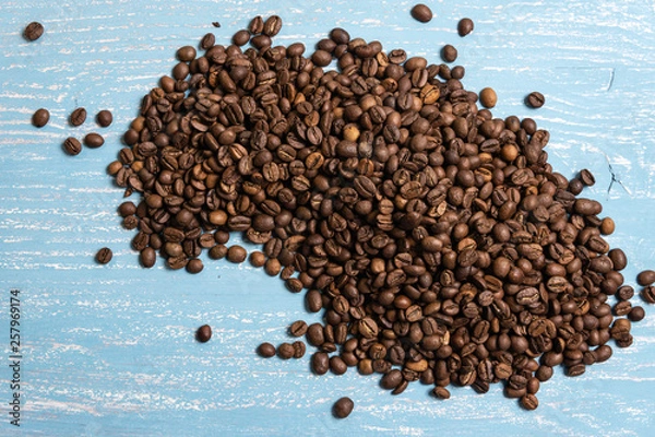 Fototapeta Roasted coffee beans in bulk on a blue wooden background