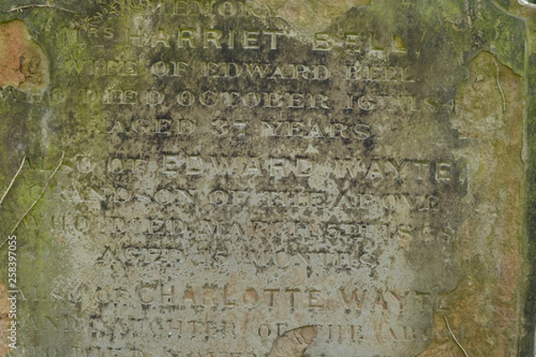 Fototapeta An Old Gravestone surface with text letters on it, close up