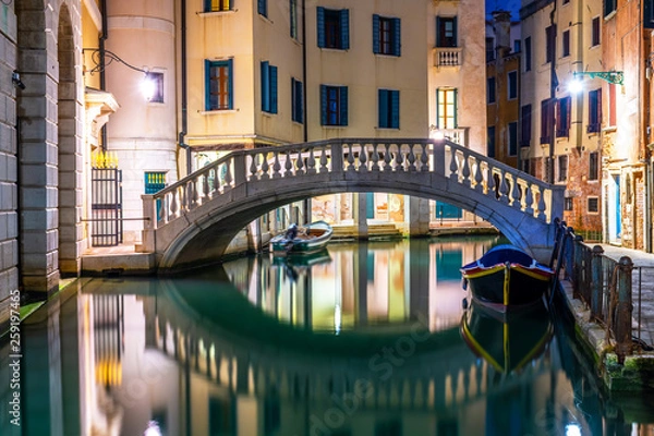 Fototapeta Canal in Venice at night with moored gondolas, Italy