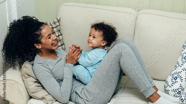 Fototapeta Mother playing with baby boy lying on sofa