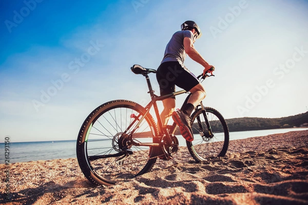 Fototapeta Man ride mountain bike on the beach. Sport and active life concept.